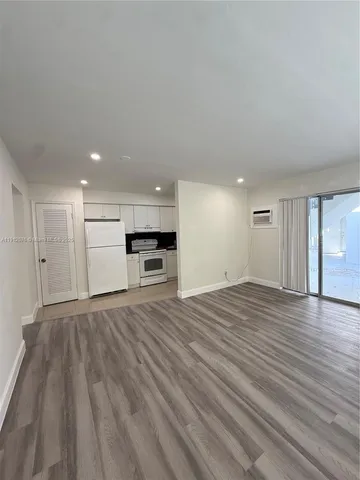 a view of empty room with kitchen and window