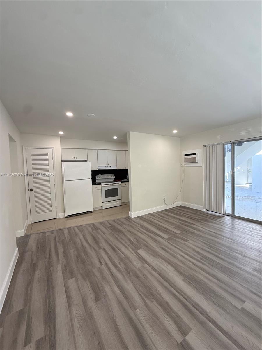 a view of empty room with kitchen and window