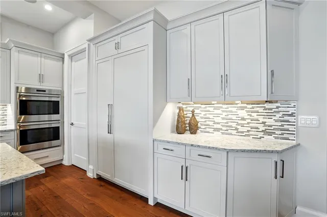 a view of kitchen with granite countertop white cabinets and stainless steel appliances