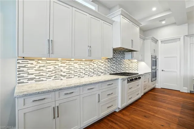 a kitchen with granite countertop white cabinets and white appliances