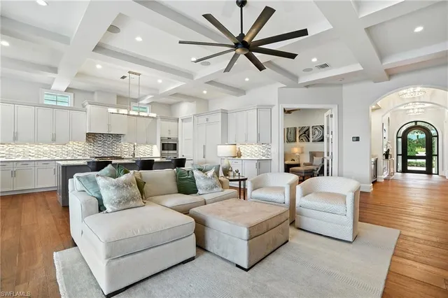 a living room with furniture kitchen view and a chandelier