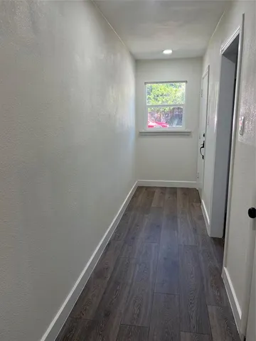 a view of a hallway with wooden floor and window