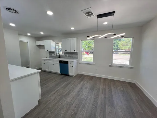 an open kitchen with kitchen island wooden floors and stainless steel appliances