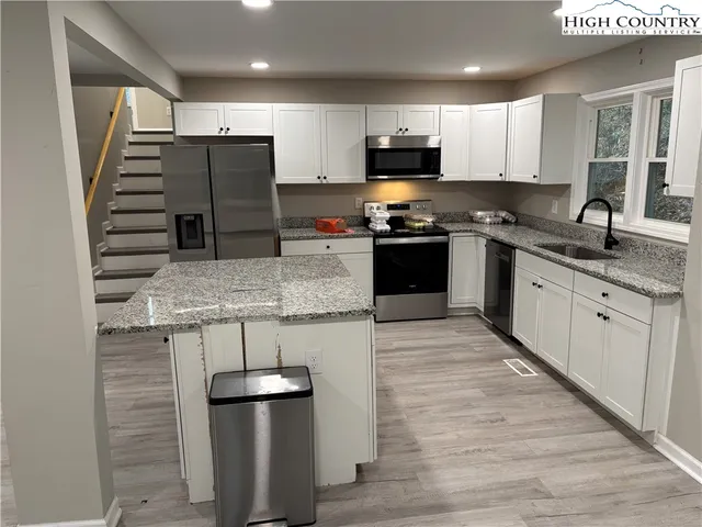 a kitchen with stainless steel appliances kitchen island granite countertop a refrigerator and a stove top oven