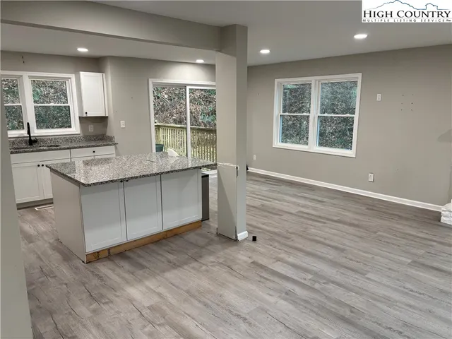 a view of a kitchen with stainless steel appliances granite countertop a stove a sink and a large window