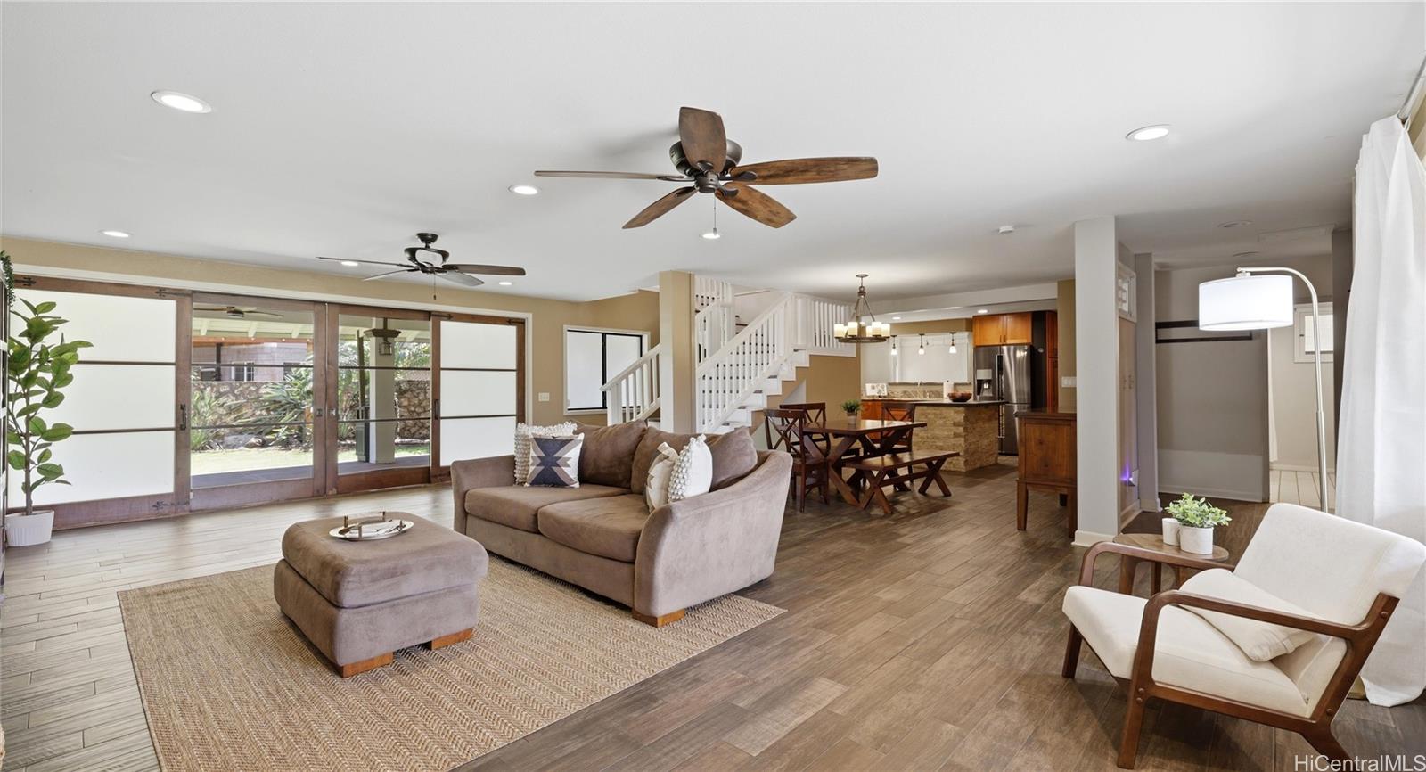 91-779 Fort Weaver Road Ewa Beach, HI 96706 - Photo 6 of 25 Open-concept living room featuring dual ceiling fans, modern flooring, and large sliding doors to the backyard.