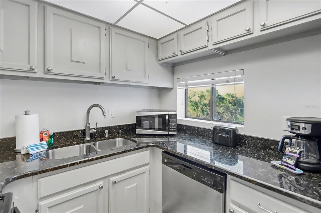 6157 Midnight Pass Road, Unit E23 Sarasota, FL 34242 - Photo 15 of 49 a kitchen with stainless steel appliances granite countertop a sink a stove and cabinets