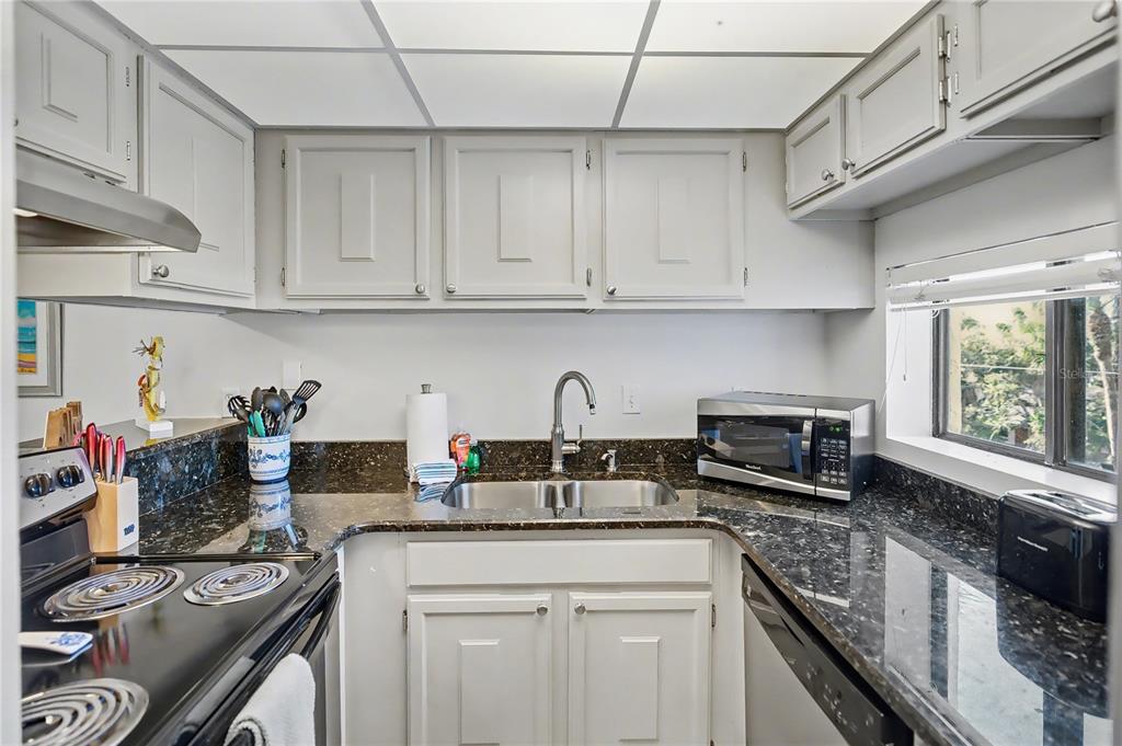6157 Midnight Pass Road, Unit E23 Sarasota, FL 34242 - Photo 16 of 49 a kitchen with stainless steel appliances granite countertop a sink stove and cabinets