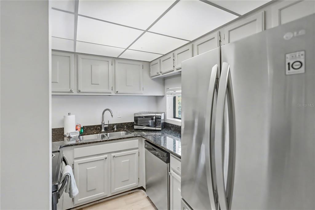 6157 Midnight Pass Road, Unit E23 Sarasota, FL 34242 - Photo 17 of 49 a kitchen with stainless steel appliances granite countertop a refrigerator sink and cabinets