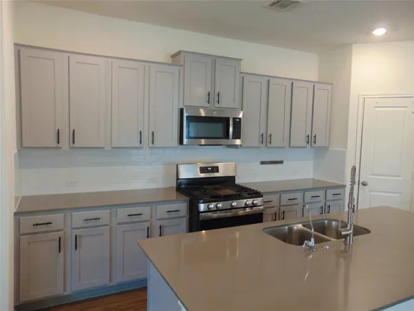 a large kitchen with stainless steel appliances kitchen island a large counter top and a wooden floors
