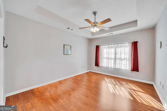 a view of an empty room with a window and wooden floor