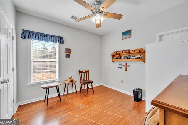 a view of a livingroom with furniture a ceiling fan and wooden floor