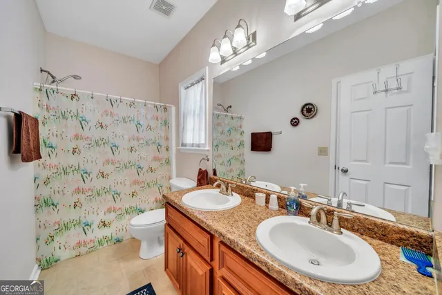 a bathroom with a double vanity sink toilet mirror and shower