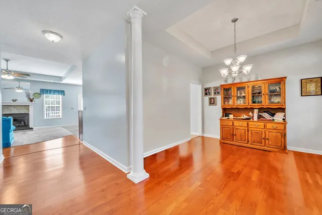 an empty room with wooden floor and kitchen view