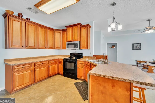 a kitchen with stainless steel appliances granite countertop a stove a sink dishwasher and a refrigerator with wooden floor