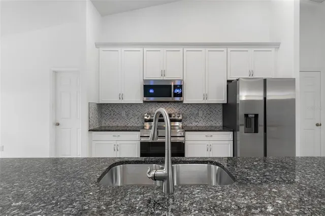a kitchen with granite countertop a stove a sink and a refrigerator