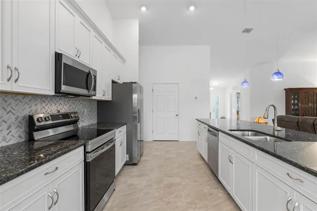 a large kitchen with stainless steel appliances granite countertop a sink stove and refrigerator