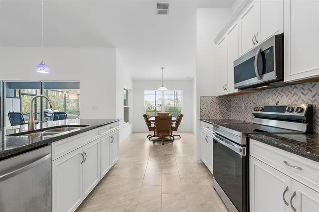 a large white kitchen with stainless steel appliances granite countertop a stove and a sink