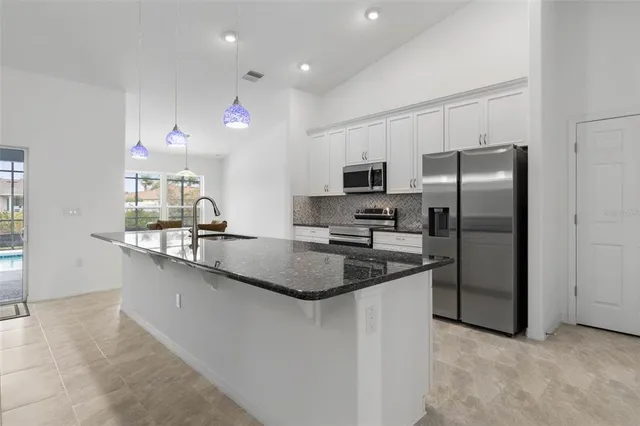 a kitchen with kitchen island granite countertop stainless steel appliances a refrigerator a sink a stove a microwave a counter space and cabinets