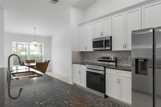 a kitchen with stainless steel appliances granite countertop a stove top oven a sink and a refrigerator