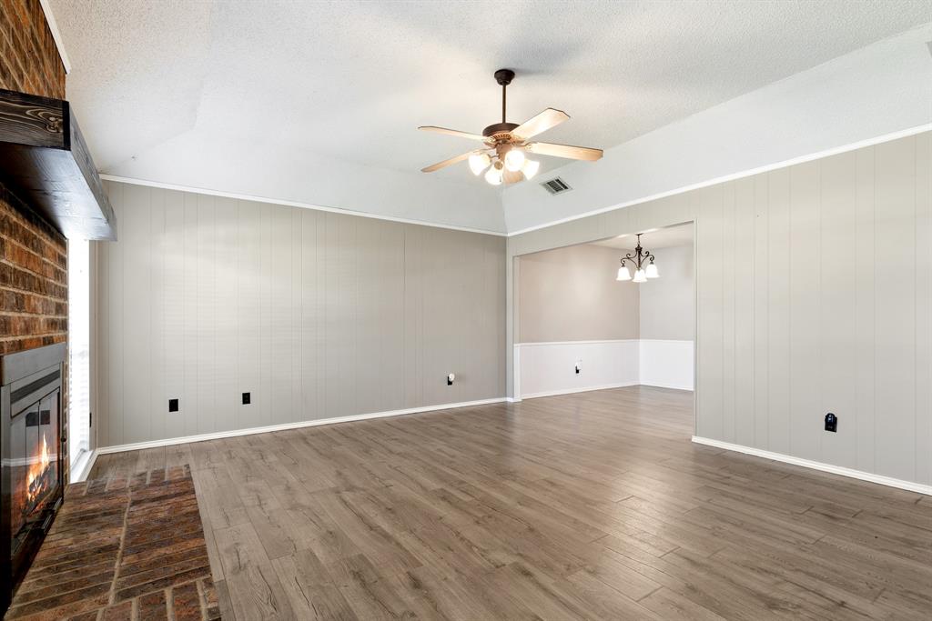 6612 Patsy Lane Watauga, TX 76148 - Photo 4 of 32 Spacious living area featuring wood-finish flooring, a brick fireplace with a wood mantle, and a ceiling fan with integrated lighting
