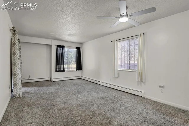 an empty room with windows and fan