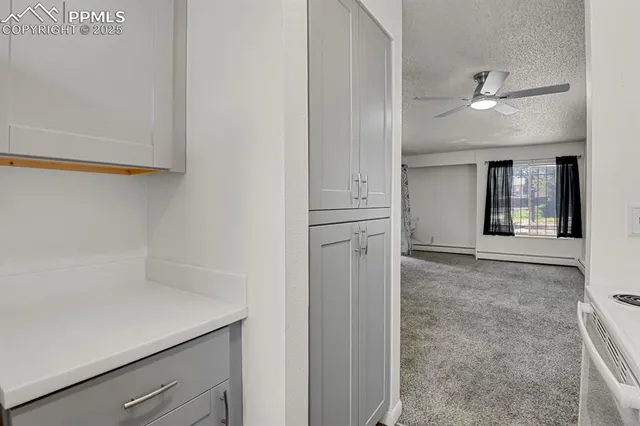 an empty room with chandelier fan and windows