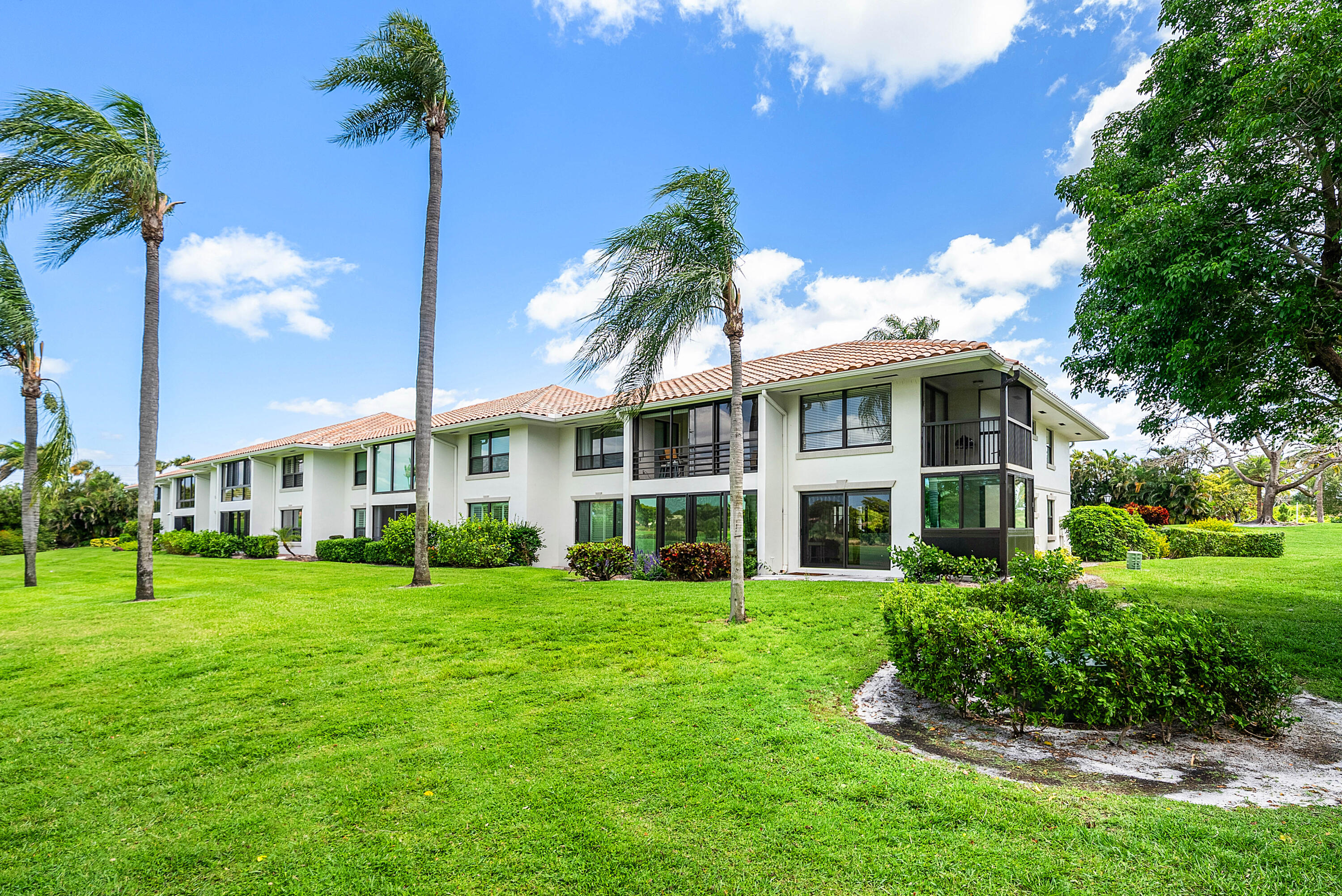 10111 Quail Covey Road, Unit HIBISCUS N Boynton Beach, FL 33436 - Photo 34 of 50 a view of a building with a big yard and palm trees