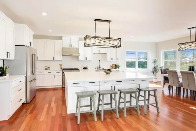 a kitchen with stainless steel appliances a dining table chairs stove and white cabinets