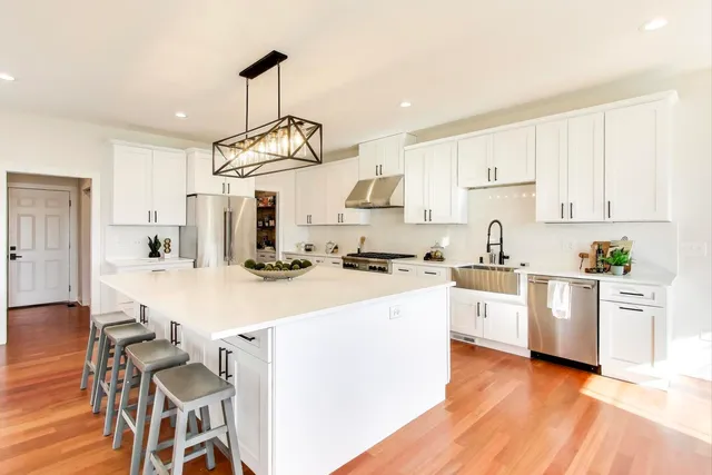 a kitchen with white cabinets stainless steel appliances and wooden floor