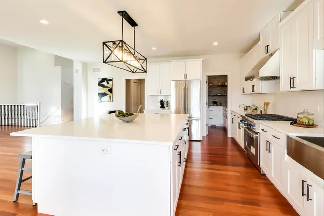 a large kitchen with stainless steel appliances a large counter top a stove a chimney a sink and dishwasher