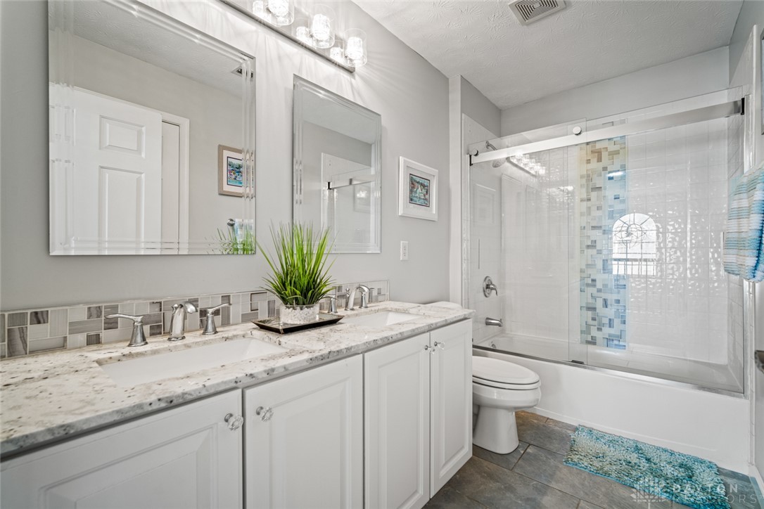 55 Janney Lane Springboro, OH 45066 - Photo 23 of 38 This sleek bathroom features a double vanity and a glass-enclosed shower-tub combination.