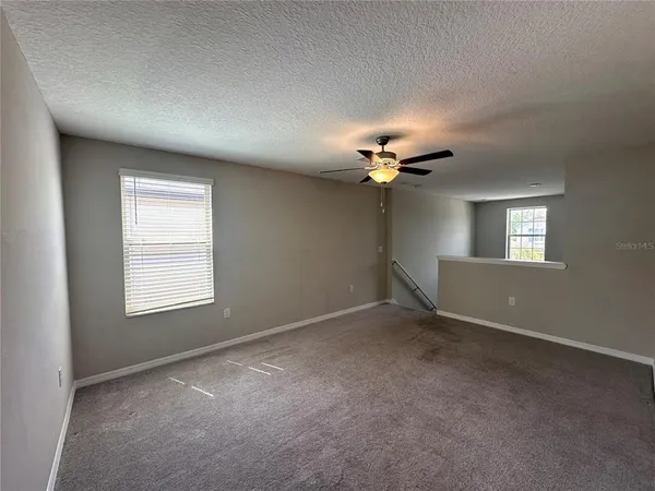 an empty room with windows and fan