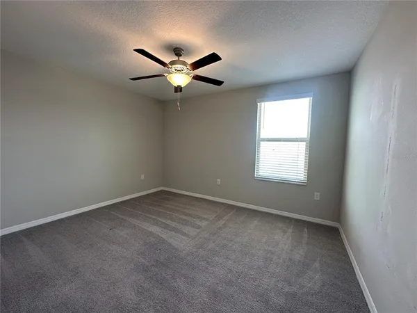 an empty room with closet and ceiling fan