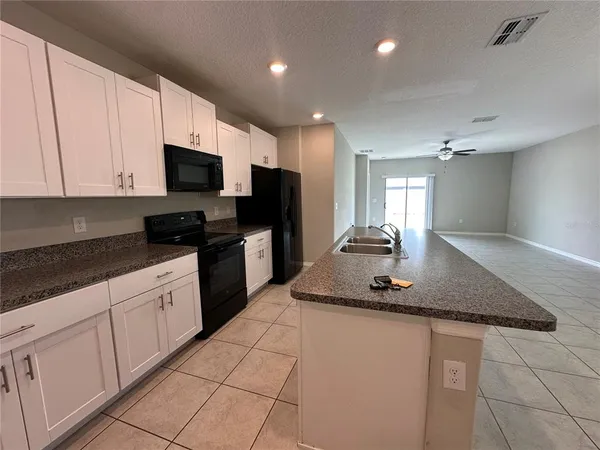 a kitchen with kitchen island granite countertop a sink a stove and cabinets