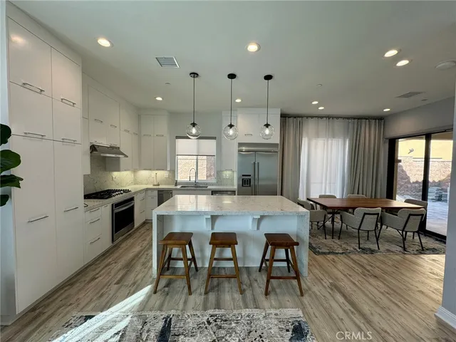 a kitchen with stainless steel appliances granite countertop dining table chairs stove refrigerator and cabinets