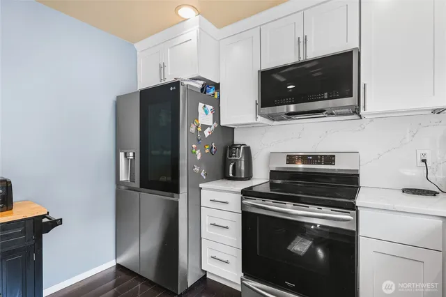 a kitchen with stainless steel appliances white cabinets and a stove a refrigerator with wooden floor