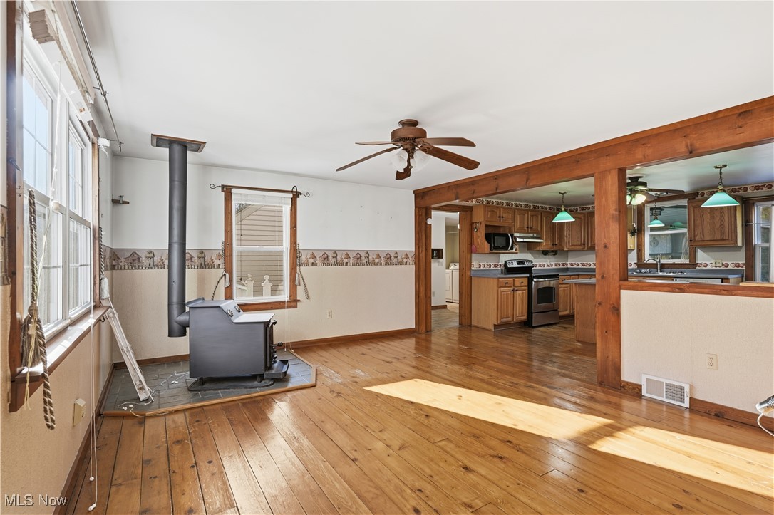 3275 Ranfield Road Kent, OH 44240 - Photo 14 of 33 Unfurnished living room featuring a wood stove, light wood-style flooring, and ceiling fan