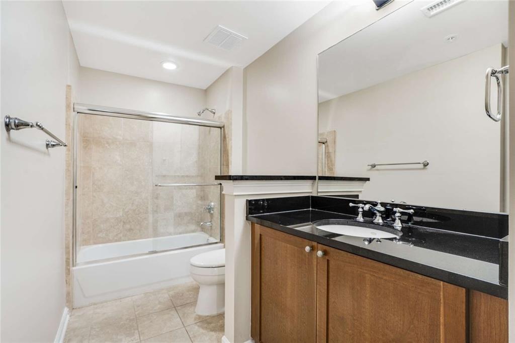 3275 Lenox Road Northeast, Unit 302 Atlanta, GA 30324 - Photo 23 of 50 a bathroom with a granite countertop sink a toilet a mirror and shower