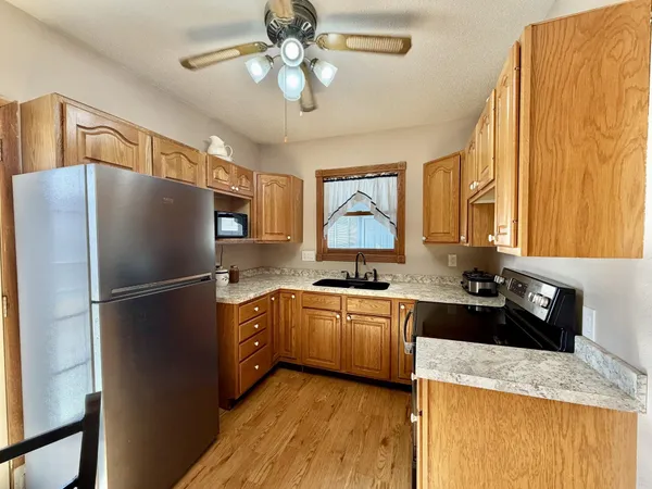 a kitchen with stainless steel appliances granite countertop a refrigerator a stove a sink dishwasher and a oven with wooden floor
