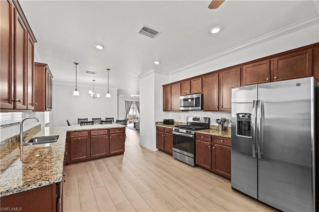17549 Timberline Parkway Babcock Ranch, FL 33982 - Photo 6 of 39 a kitchen with stainless steel appliances granite countertop a stove top oven a refrigerator a sink and dishwasher with wooden floor