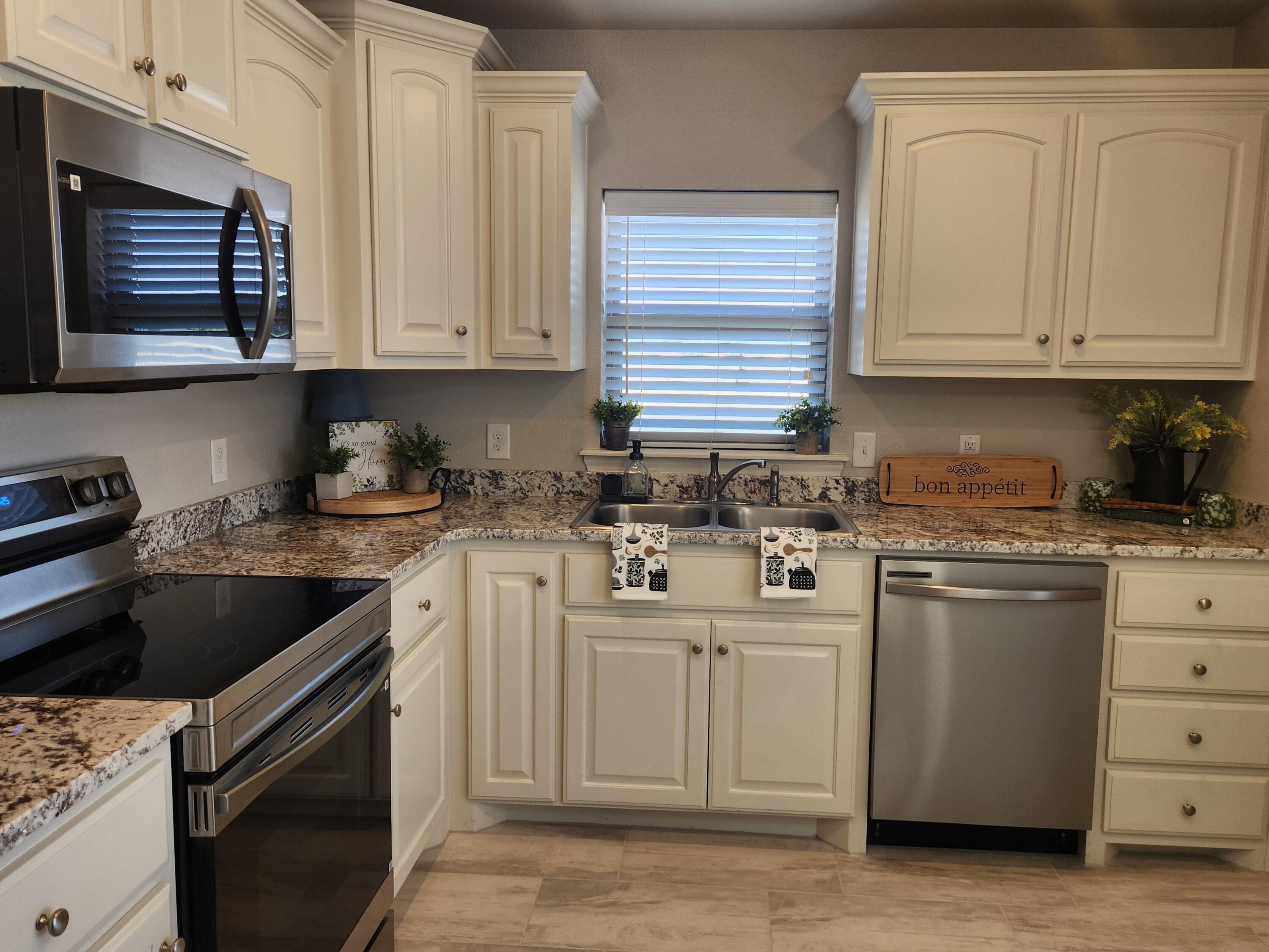 8702 13th Street Lubbock, TX 79416 - Photo 4 of 25 a kitchen with white cabinets and white appliances