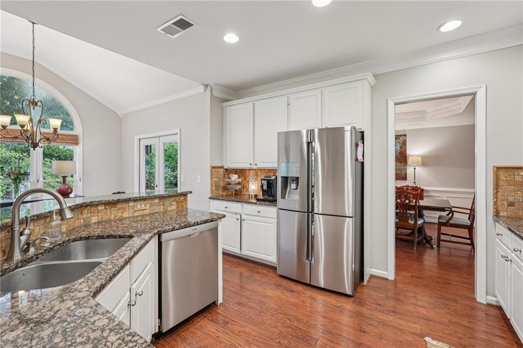 3820 Ridge Point Drive Suwanee, GA 30024 - Photo 12 of 41 a kitchen with stainless steel appliances granite countertop a refrigerator a stove a sink and a dining table with wooden floor