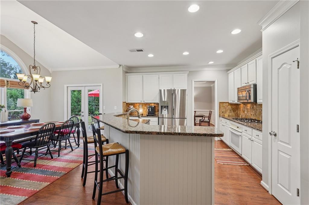 3820 Ridge Point Drive Suwanee, GA 30024 - Photo 10 of 41 a kitchen with stainless steel appliances kitchen island granite countertop a stove a refrigerator a kitchen island a dining table and chairs with wooden floor