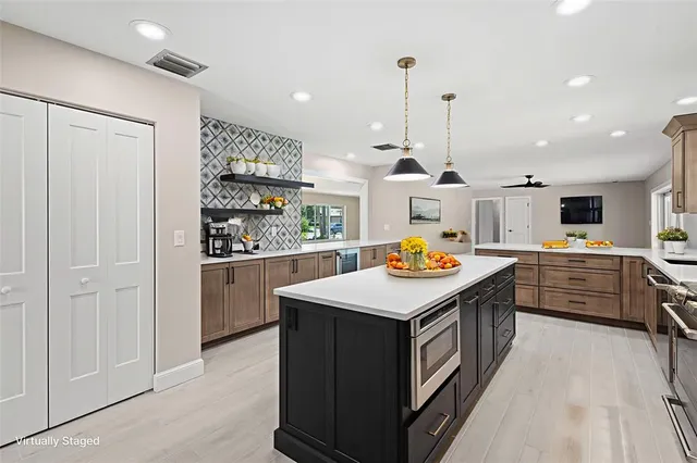 a kitchen with kitchen island stainless steel appliances a stove sink and cabinets