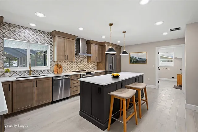 a kitchen with stainless steel appliances kitchen island granite countertop a table chairs sink and wooden floor
