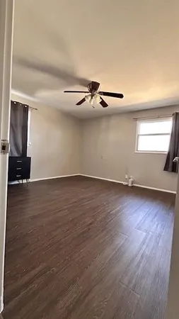 an empty room with wooden floor a ceiling fan and windows
