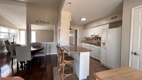 a kitchen with stainless steel appliances a dining table chairs and a refrigerator