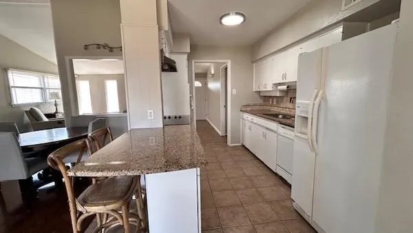 a kitchen with stainless steel appliances granite countertop a stove top oven a sink a dining table and chairs