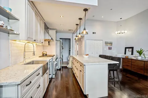 a large kitchen with stainless steel appliances a stove a sink dishwasher and a dining table with wooden floor